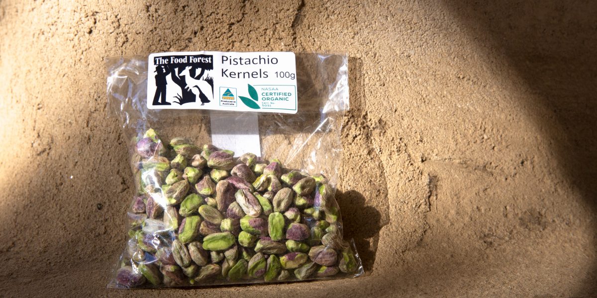 A bag of pistachios centres the photo. This product is organic produced by The Food Forest 