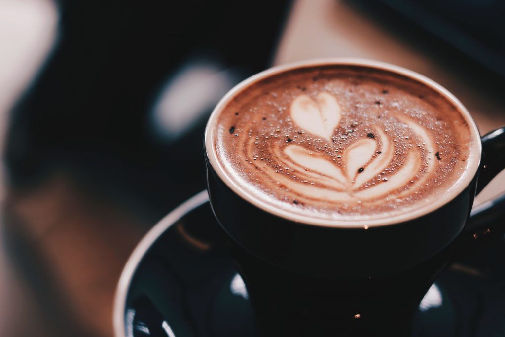 An organic coffee in a black cup placed on a wooden bench